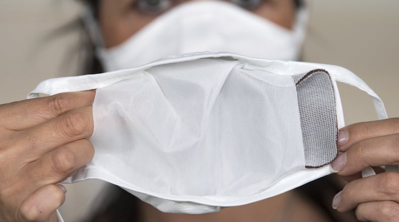 Jana Seidel, employee of the automotive supplier C.H. Müller GmbH, demonstrates the use of a reusable mask with a copper-containing filter. HENDRIK SCHMIDT / PICTURE-ALLIANCE / DPA / AP IMAGES
