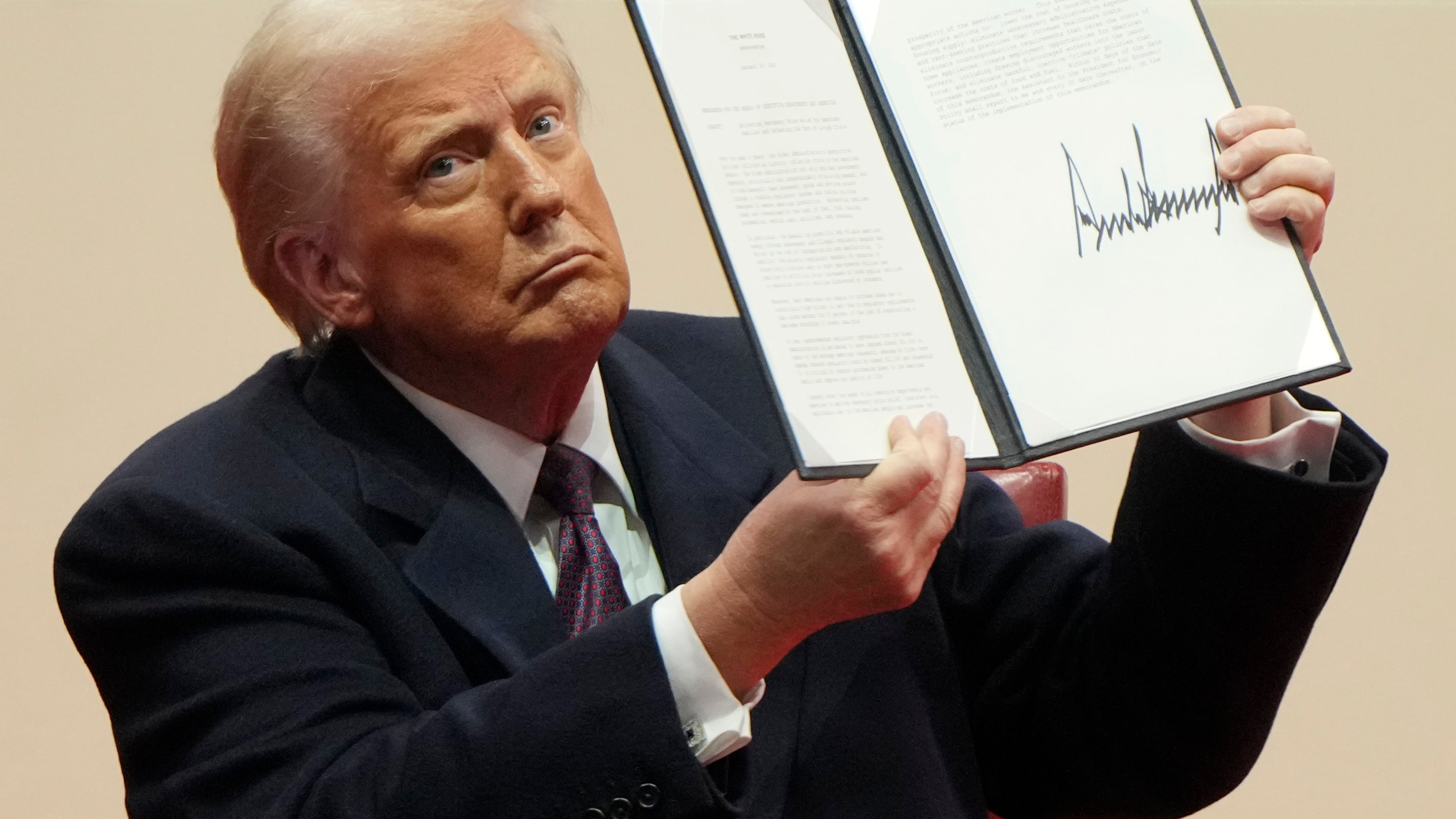 FILE - President Donald Trump holds up an executive order after signing it at an indoor Presidential Inauguration parade event in Washington, Jan. 20, 2025. (AP Photo/Matt Rourke, File)