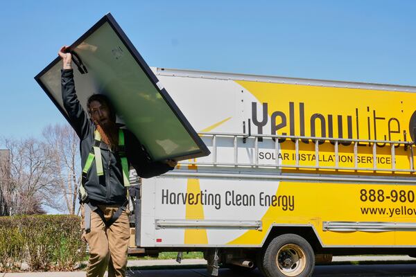 Theodore Tanczuk, of solar installer YellowLite, carries a panel from his truck to the roof of a home in Lakewood, Ohio, Wednesday, April 16, 2025. (AP Photo/Sue Ogrocki)