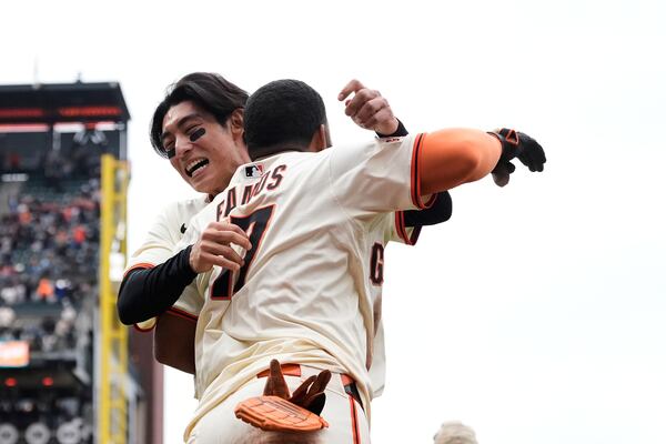 San Francisco Giants' Heliot Ramos (17) is congratulated by Jung Hoo Lee after after scoring the game-winning run against the Texas Rangers during the ninth inning of a baseball game Sunday, April 27, 2025, in San Francisco. (AP Photo/Godofredo A. Vásquez)