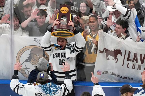 Western Michigan's Tim Washe (16) holds up the trophy while celebrating his team's victory over Boston University in the championship game of the NCAA Frozen Four men's college hockey tournament, Saturday, April 12, 2025, in St. Louis (AP Photo/Jeff Roberson)