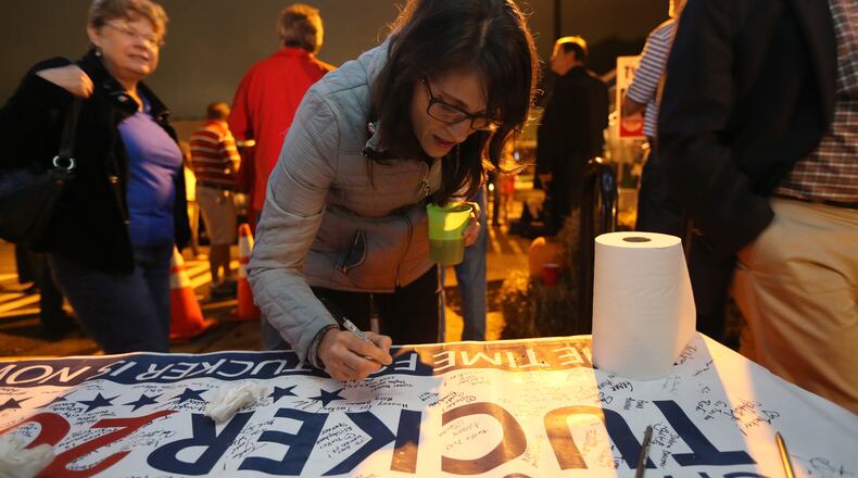 Susan Fernandez signs "Tucker Yes" on a banner Tuesday evening while attending an election night party on Main Street of what will become the city of Tucker. Ben Gray / bgray@ajc.com