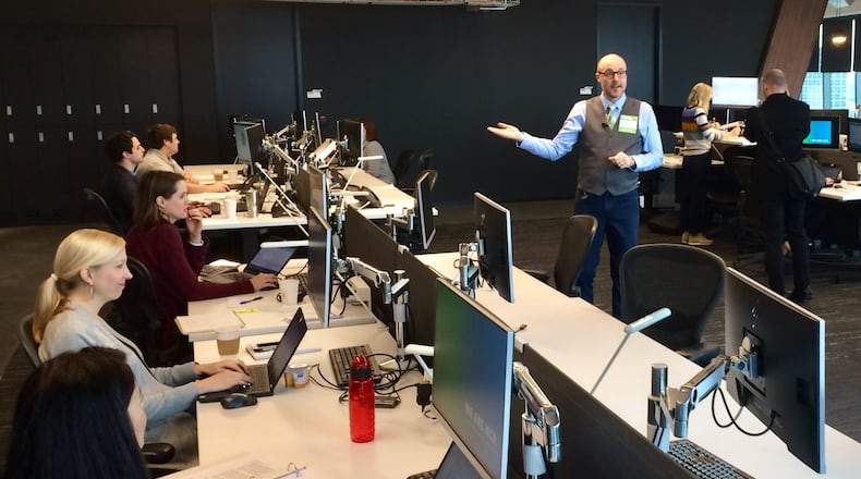 Kevin Finke, right, an NCR executive and head of campus and cultural experiences, shows of some of the workstations in the financial technology company’s Midtown Atlanta headquarters, which opened in January 2017. Tuesday, Feb. 13, 2018. J. Scott Trubey/strubey@ajc.com