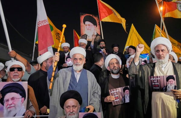 Iraqis Shiite clerics hold a portrait of Iran's Supreme Leader Ayatollah Ali Khamenei during a protest against Israeli attacks on multiple cities across Iran, at a bridge leading to the fortified Green Zone where the U.S. embassy is located in Baghdad, Iraq, Thursday, June 19, 2025. (AP Photo/Hadi Mizban)