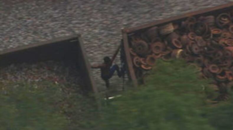 A man trying to escape police in Charlotte, North Carolina, ditches his car and tries to make a getaway by jumping aboard a train. WSOC-TV’s news chopper captured this grainy image of the man hanging on between two train cars.