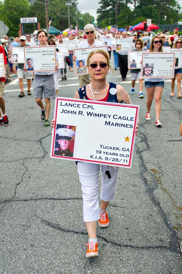 May 25, 2015 Dacula - Carolyn Cagle (center) carries a photo of her son John Wimpey Cagle, who was killed in action in 2011, as she marches with the Fallen Heroes of Georgia during the annual Dacula Memorial Day Parade on Monday, May 25, 2015. The parade, now in its 22nd year, remains the only Memorial Day parade in Metro Atlanta, largest in the the state of Georgia and one of the largest in the nation with more than 150 units participating this year. JONATHAN PHILLIPS / SPECIAL