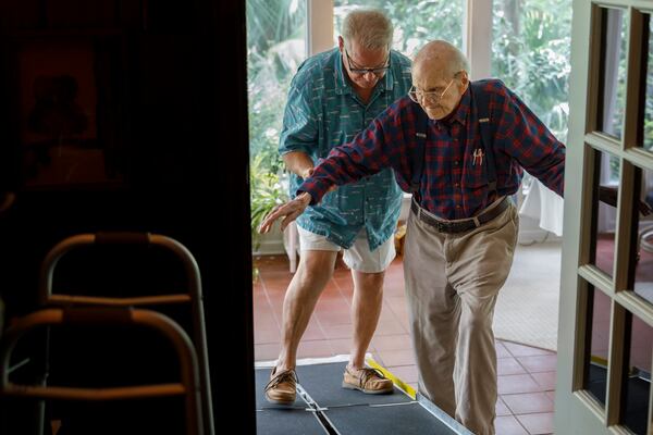Avery Low, right, is assisted by his son Jamie Low as he enters the family home in Savannah. (Walker Smith for the AJC)