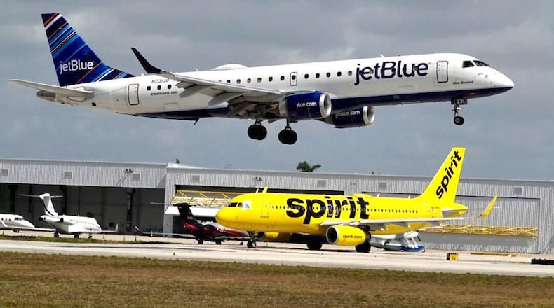 A JetBlue airliner lands past a Spirit Airlines jet on taxi way at Fort Lauderdale Hollywood International Airport on Monday, April 25, 2022. (Joe Cavaretta/Sun Sentinel/TNS)