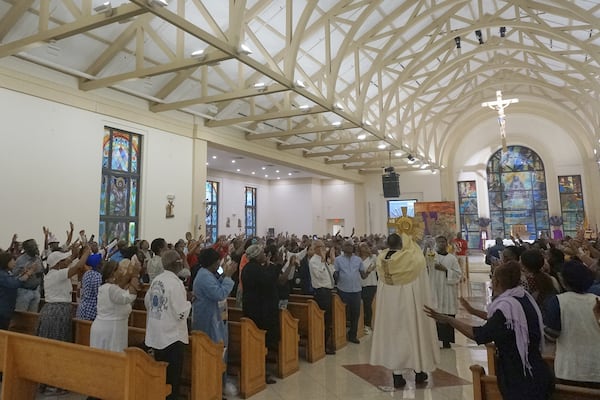 Faithful pray as the Blessed Sacrament is carried among the pews during a Lent revival faith service at Notre Dame d'Haiti Catholic church, March 29, 2025, in Miami. (AP Photo/Giovanna Dell'Orto)