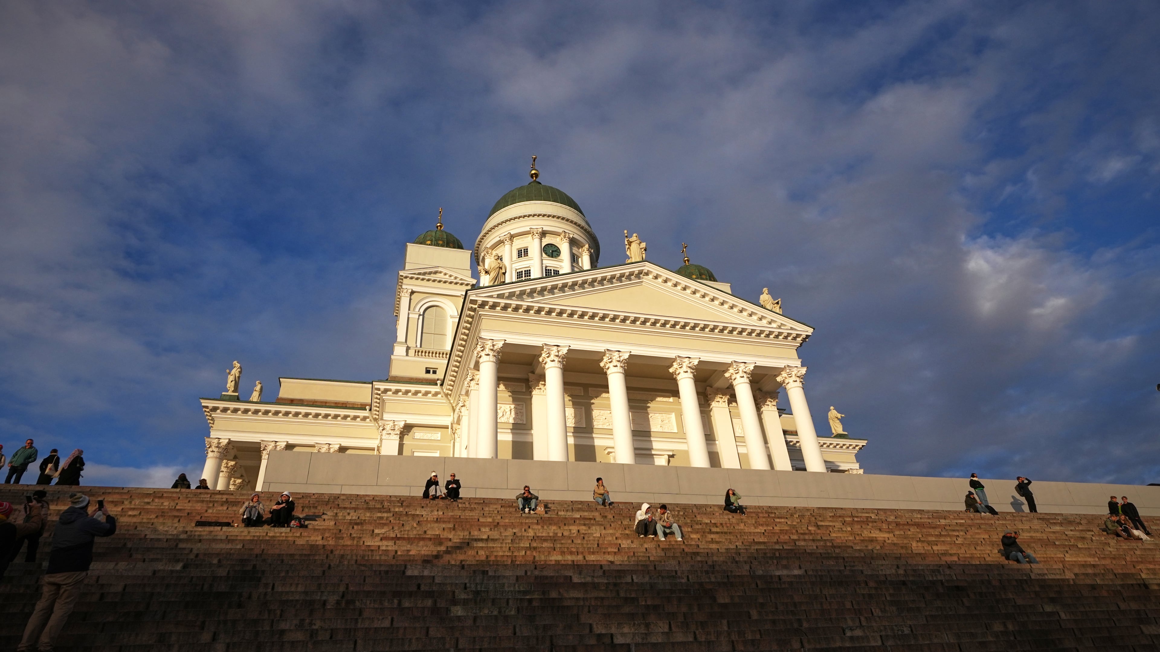 People enjoy the sunny weather with the Helsinki Cathedral of the background in Helsinki, Finland, Friday, Nov. 14, 2025. (AP Photo/Sergei Grits)