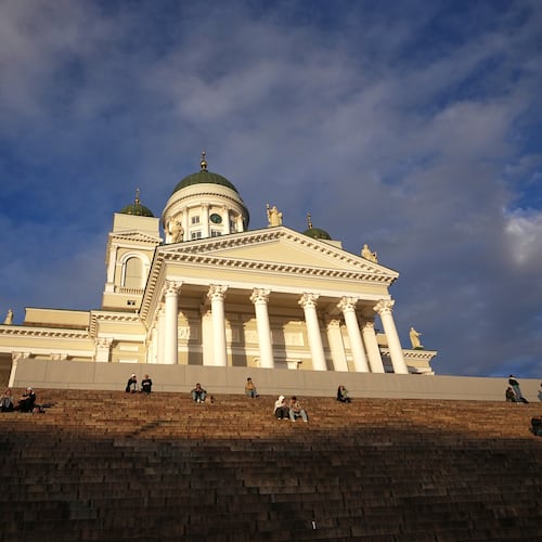 People enjoy the sunny weather with the Helsinki Cathedral of the background in Helsinki, Finland, Friday, Nov. 14, 2025. (AP Photo/Sergei Grits)