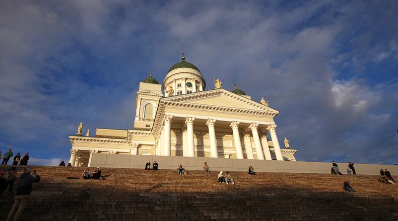People enjoy the sunny weather with the Helsinki Cathedral of the background in Helsinki, Finland, Friday, Nov. 14, 2025. (AP Photo/Sergei Grits)