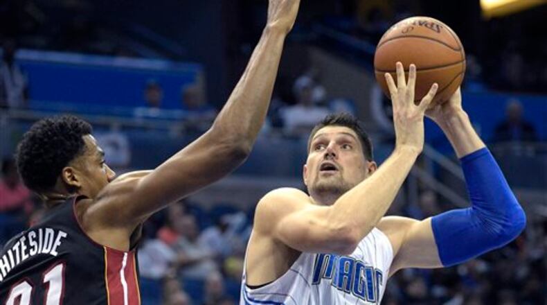Orlando Magic center Nikola Vucevic, right, goes up for a shot in front of Miami Heat center Hassan Whiteside (21) during the second half of an NBA basketball game in Orlando, Fla., Saturday, Dec. 26, 2015. The Heat won 108-101. (AP Photo/Phelan M. Ebenhack)