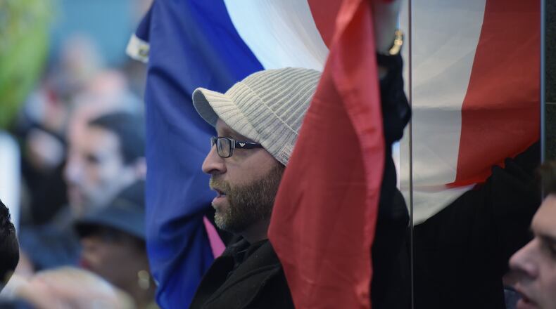 Samy Onsi of Smyrna, holds the French tri-color flag while singing the French national anthem. A crowd of about 400 people gathered at the French Consulate in Atlanta on Sunday to rally in support of the victims of the Paris terrorist attack. Kent D. Johnson, kdjohnson@ajc.com