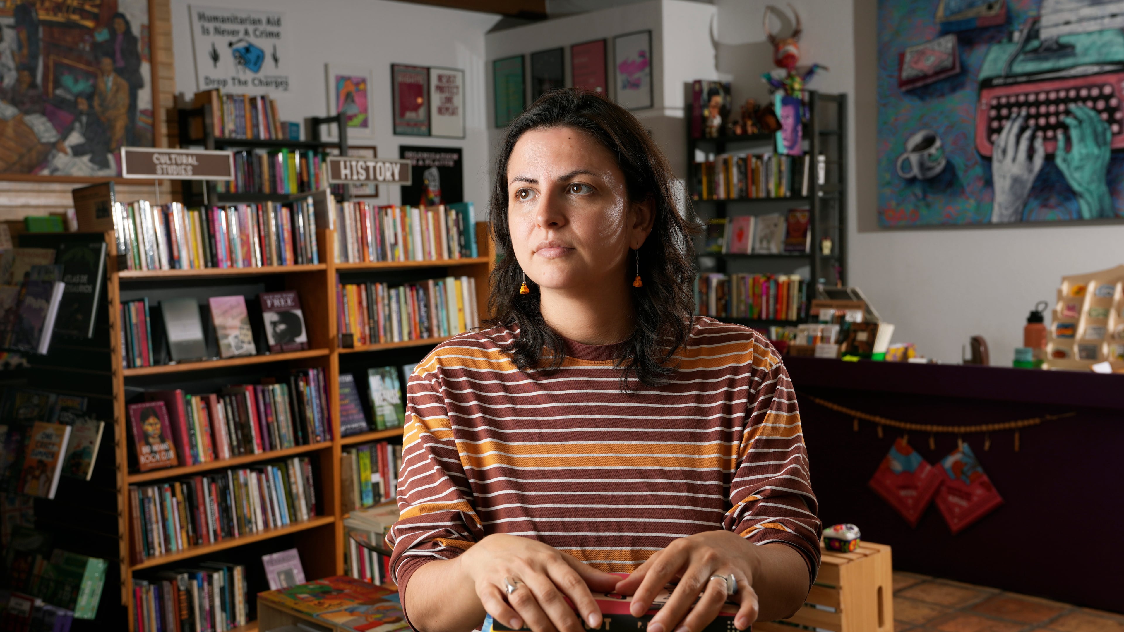 Chawa Magaña, owner of Palabras Bilingual Bookstore, poses with a few of her favorite books Monday, Oct. 6, 2025, in Phoenix. (AP Photo/Ross D. Franklin)