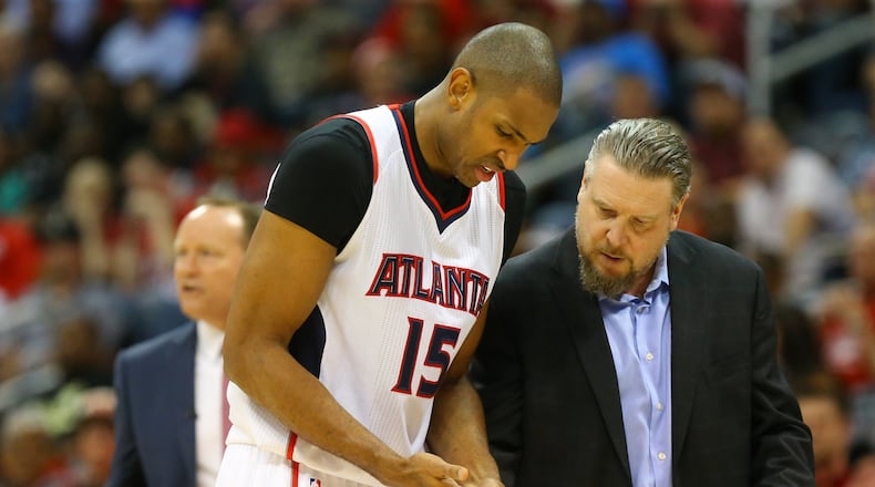 Hawks head trainer Wally Blase checks center Al Horford’s hand after he dislocated his pinky finger against the Nets during an NBA playoff basketball game on Sunday, April 19, 2015, in Atlanta. Curtis Compton / ccompton@ajc.com