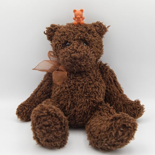 A miniature plastic teddy bear sits atop a stuffed teddy bear in Phoenix, Tuesday, April 14, 2026. (AP Photo/Dario Lopez-Mills)