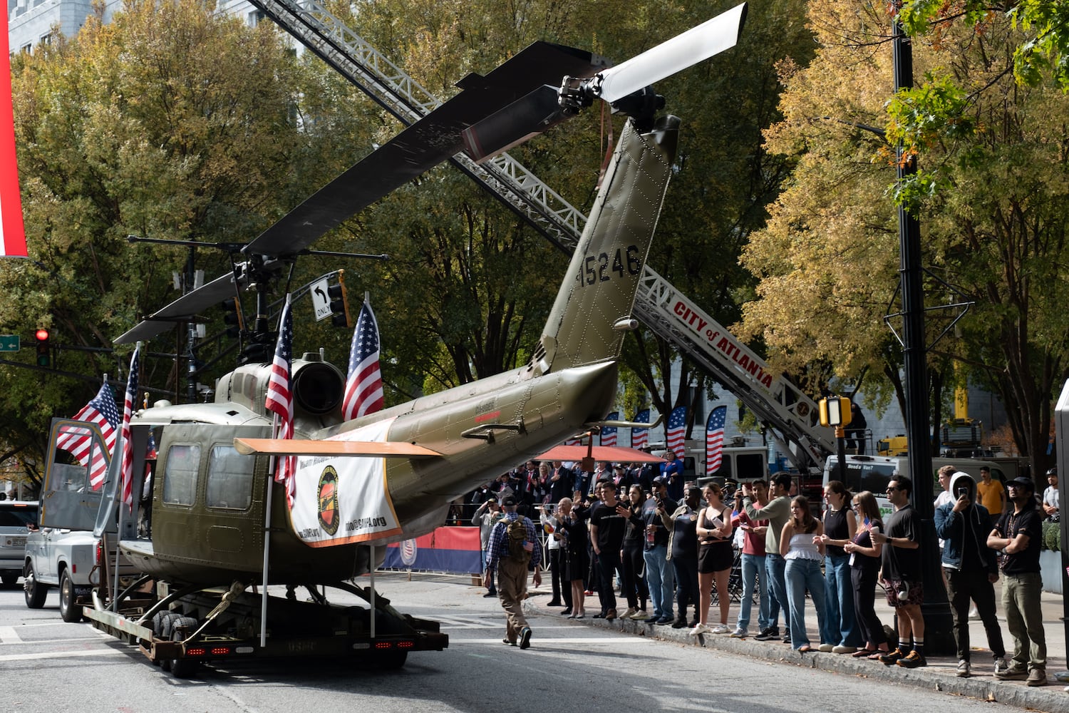Spectators watch a Huey helicopter make it’s way down Peachtree Street during the Georgia Veterans Day Parade in Midtown Atlanta on Saturday, Nov. 8, 2025.   Ben Gray for the Atlanta Journal-Constitution