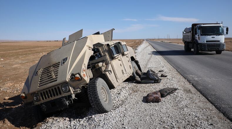 A truck drives past a damaged Humvee abandoned by retreating Syrian Democratic Forces (SDF) along a road between government-controlled Raqqa and SDF-controlled Hassakeh in northeastern Syria, Tuesday, Jan. 20, 2026. (AP Photo/Omar Albam)