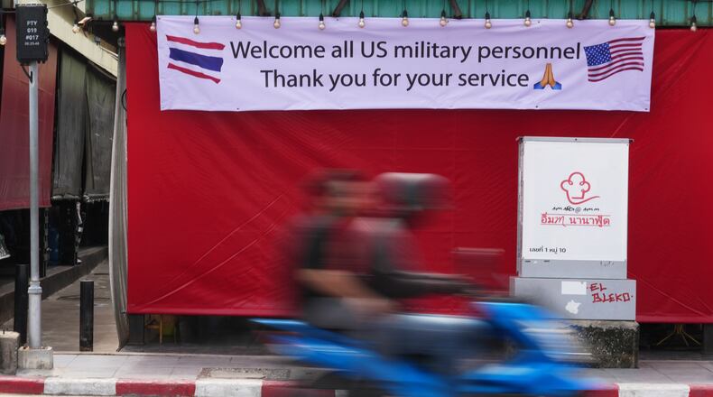 A motorcycle taxi drives past a banner in Pattaya, Thailand, Tuesday, Sept. 1, 2026. (AP Photo/Sakchai Lalit)