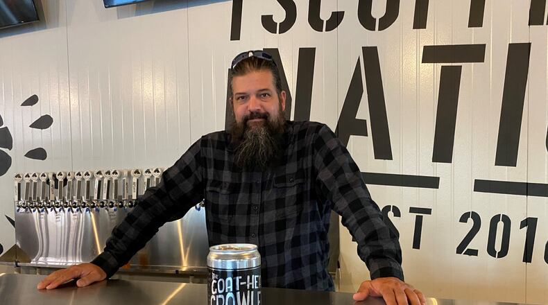 Scofflaw Brewing co-founder and chief brewing officer Travis Herman, shown with a quart growler, is in the taproom at the new Dr. Scofflaw’s Laboratory and Beer Garden, which is dedicated to experimentation. Bob Townsend for The AJC