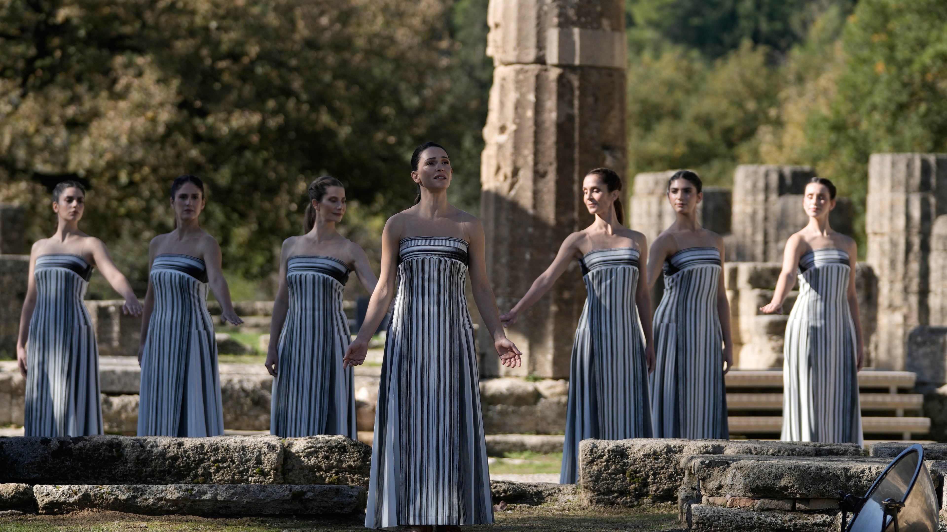 Actor Mary Mina playing the role of high priestess, center, performs during a rehearsal ahead of the flame lighting for the Milan Cortina 2026 Winter Olympics, at the Ancient Olympia site, Greece, Monday, Nov. 24, 2025. (AP Photo/Thanassis Stavrakis)