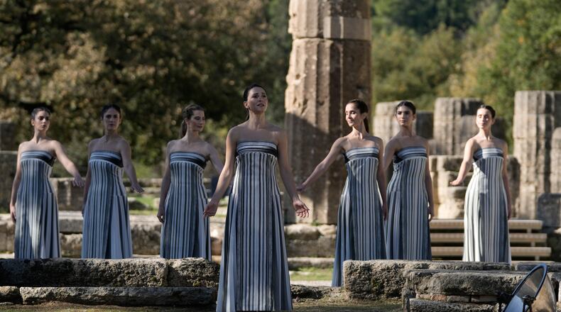 Actor Mary Mina playing the role of high priestess, center, performs during a rehearsal ahead of the flame lighting for the Milan Cortina 2026 Winter Olympics, at the Ancient Olympia site, Greece, Monday, Nov. 24, 2025. (AP Photo/Thanassis Stavrakis)