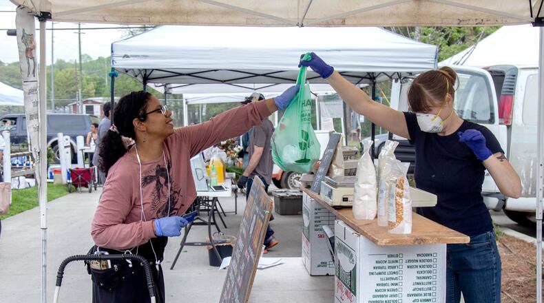 Grant Park Farmers Market’s personal shopper Mercedes Melendez (L) buys groceries for her client Sunday, March 29, 2020. STEVE SCHAEFER / SPECIAL TO THE AJC