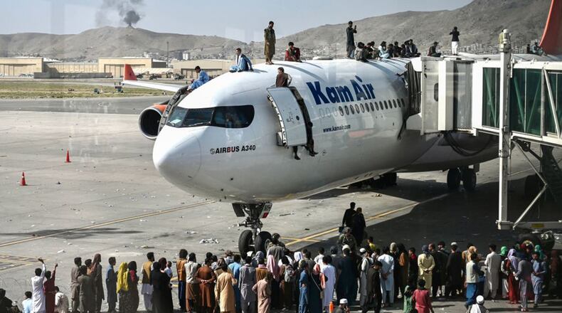 Afghan people climb atop a plane Monday as thousands of people mobbed Kabul's airport trying to flee after the country's government collapsed and the Taliban moved into the capital city. (Wakil Kohsar/AFP via Getty Images/TNS)