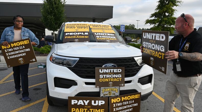 August 4, 2022 Atlanta - Eric Massaro (right) and Aluana Freeman, both members of Teamsters and UPS employees, hold a sign in the employee parking lot after holding a contract rally inside UPS SMART Hub in Atlanta on Thursday, August 4, 2022. The Teamsters were holding a contract rally among workers in preparation for negotiations with UPS coming up over the next year. (Hyosub Shin / Hyosub.Shin@ajc.com)
