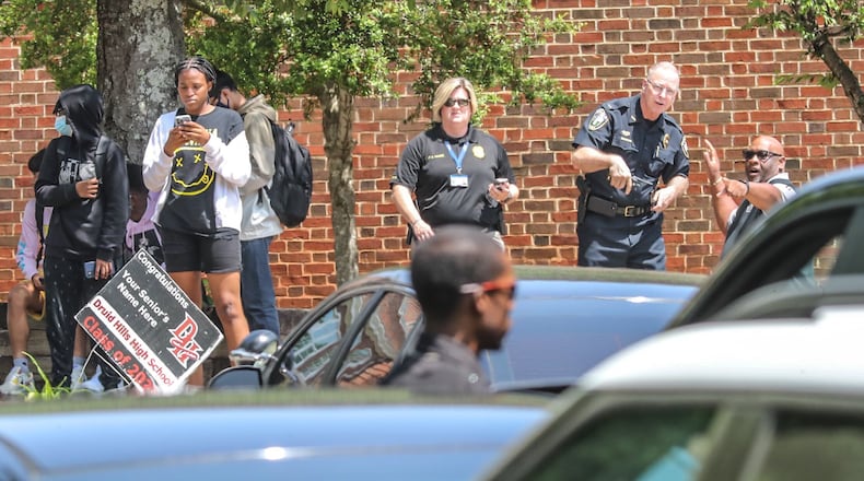 Police officials gather outside of Druid Hills High School after an armed suspect was reported in the area Thursday morning. The suspect, a student at the school, was arrested just before 4 p.m.