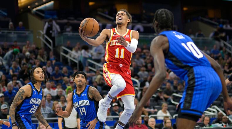 Atlanta Hawks guard Trae Young (11) goes up for a shot between Orlando Magic guard Markelle Fultz (20), guard Gary Harris (14) and center Bol Bol (10) during the first half of an NBA basketball game Wednesday, Nov. 30, 2022, in Orlando, Fla. (AP Photo/Phelan M. Ebenhack)