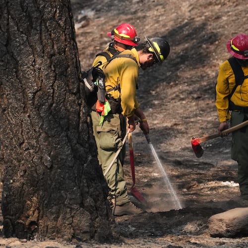 A crew does mop-up work in a burned area of Wyakin Park after a wildfire hit the northern part of Spokane, Wash., Tuesday, Aug. 4, 2026. (AP Photo/Lindsey Wasson)