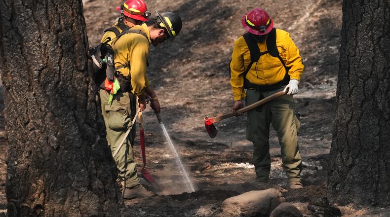 A crew does mop-up work in a burned area of Wyakin Park after a wildfire hit the northern part of Spokane, Wash., Tuesday, Aug. 4, 2026. (AP Photo/Lindsey Wasson)