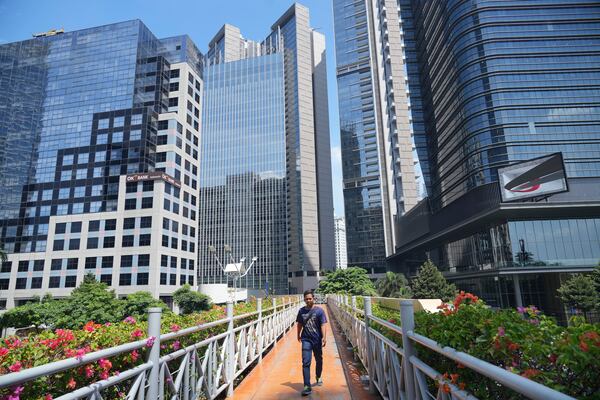 A man walks on a pedestrian bridge as tall buildings are seen in the background at the main business district in Jakarta, Indonesia, Monday, April 7, 2025. (AP Photo/Tatan Syuflana)