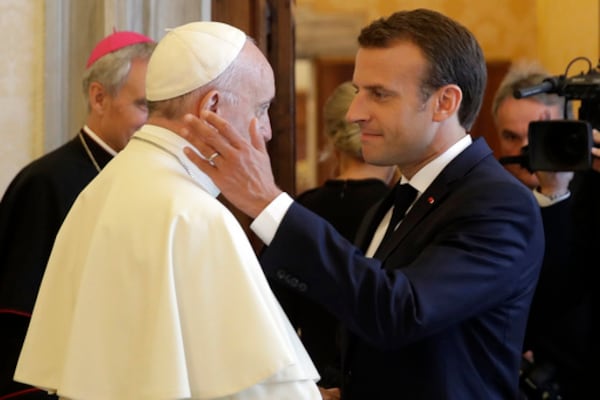 FILE - French President Emmanuel Macron, right, shakes hands with and goes to hug Pope Francis at the end of their private audience, at the Vatican, Tuesday, June 26, 2018. (Alessandra Tarantino/Pool Photo via AP, File)