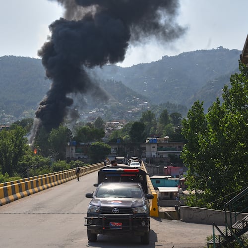 A police vehicle is parked at along a road as smoke billows after an army MI-17 helicopter crashed due to a technical fault, in Muzaffarabad, capital of Pakistan-administered Kashmir, Wednesday, June 10, 2026. (AP Photo/M.D. Mughal)