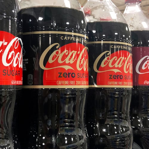 FILE - Bottles of Coca-Cola products sit on a shelf at a store in Dania Beach, Fla., Oct. 20, 2020. (AP Photo/Wilfredo Lee, File)