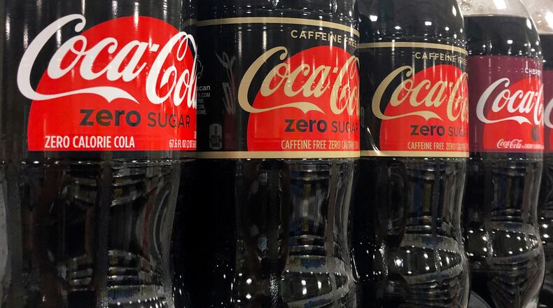 FILE - Bottles of Coca-Cola products sit on a shelf at a store in Dania Beach, Fla., Oct. 20, 2020. (AP Photo/Wilfredo Lee, File)
