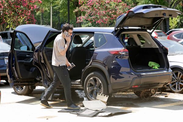 A man tries to dry his car out in a parking lot at University Place shopping center after it was flooded out during tropical storm Chantal, Monday, July 7, 2025, in Chapel Hill, N.C. (AP Photo/Chris Seward)