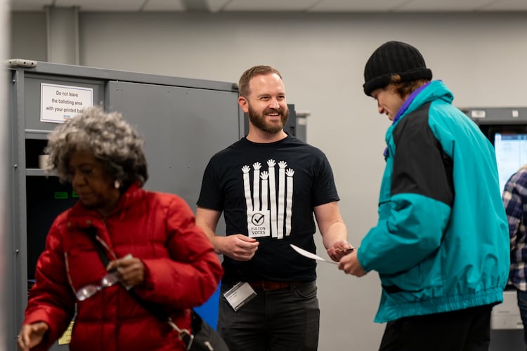 Patrick Raber (center) assists voters in casting their ballots inside the Buckhead Library voting precinct on Tuesday, Nov. 4, 2025 (Ben Hendren for the AJC)