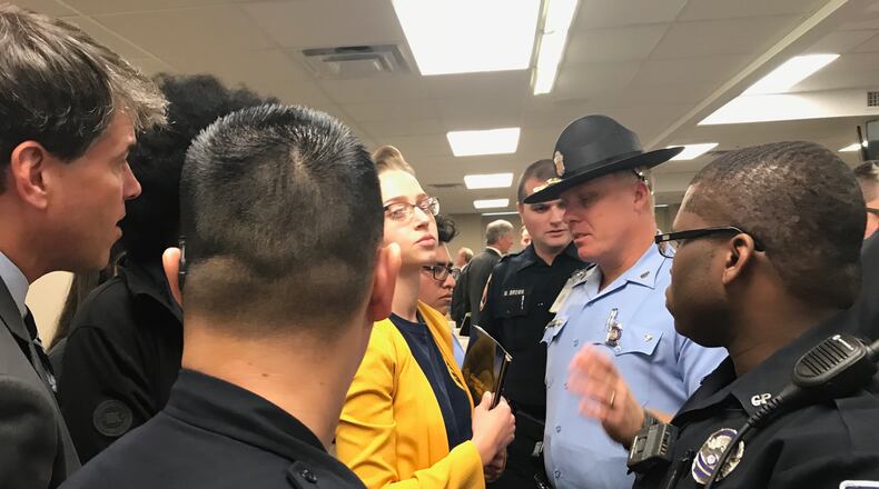 Natalie Leonard, in yellow, a fourth-year Georgia Tech student, is blocked by an officer from handing a folder with information that included a "new appeal for human rights" to Georgia Board of Regents members at its Nov. 15, 2017 meeting. ERIC STIRGUS / ESTIRGUS@AJC.COM