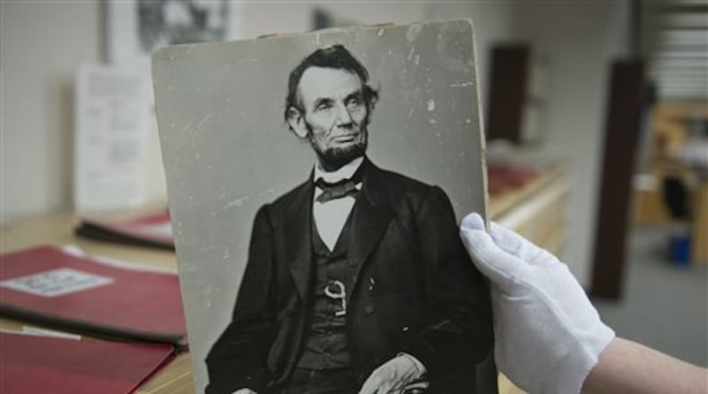 In this Monday, April 6, 2015 photo, Karen Needles holds up a photograph of President Abraham Lincoln at the National Archives in College Park, Md. Three blocks away, 150 years earlier, Lincoln was felled by an assassin's bullet. (AP Photo/Molly Riley)