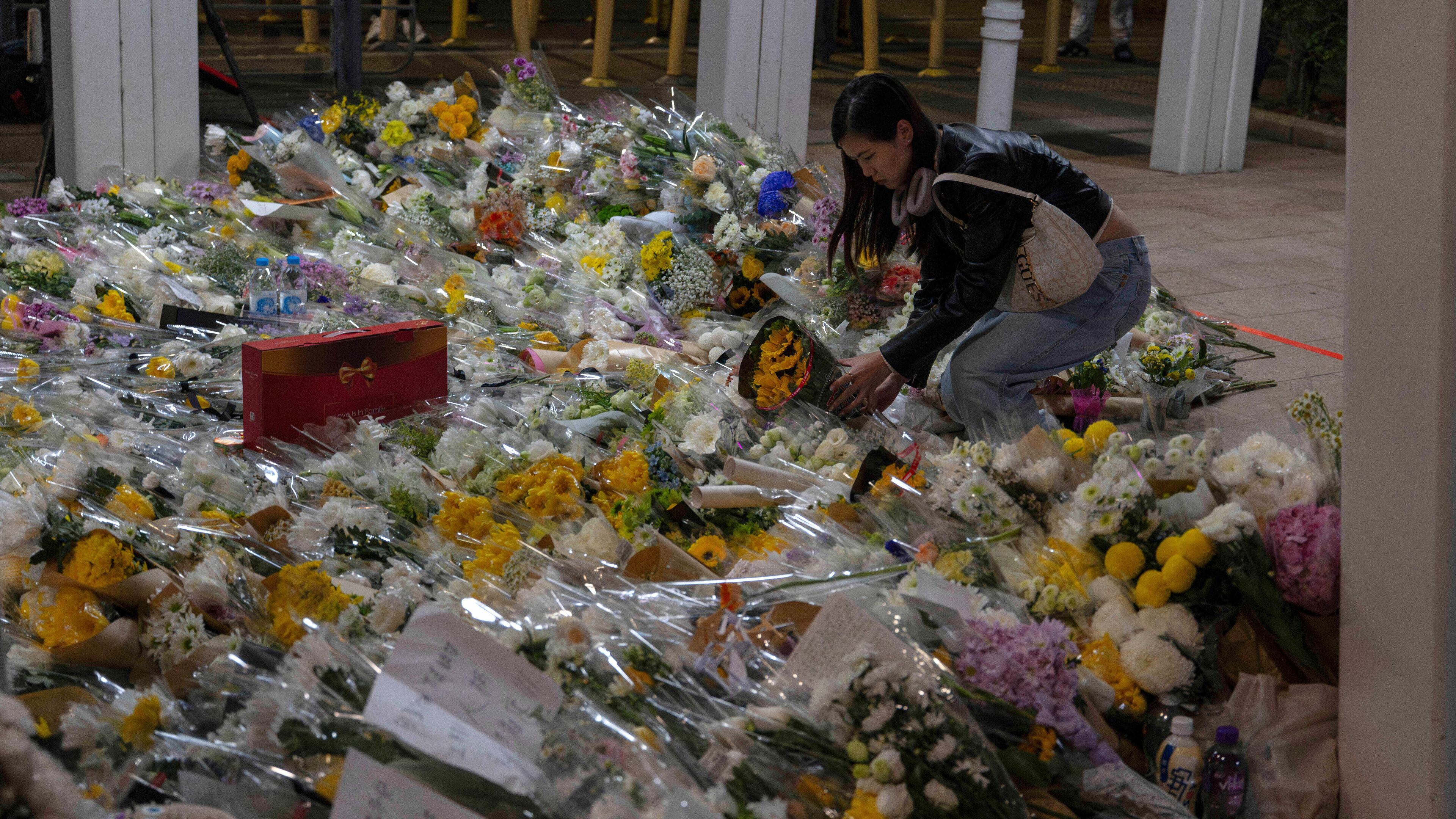 A woman lays flowers near the site of the deadly Wednesday fire at Wang Fuk Court, a residential estate in the Tai Po district of Hong Kong's New Territories on Saturday, Nov. 29, 2025. (AP Photo/Ng Han Guan)