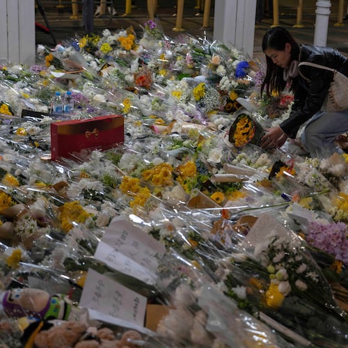 A woman lays flowers near the site of the deadly Wednesday fire at Wang Fuk Court, a residential estate in the Tai Po district of Hong Kong's New Territories on Saturday, Nov. 29, 2025. (AP Photo/Ng Han Guan)