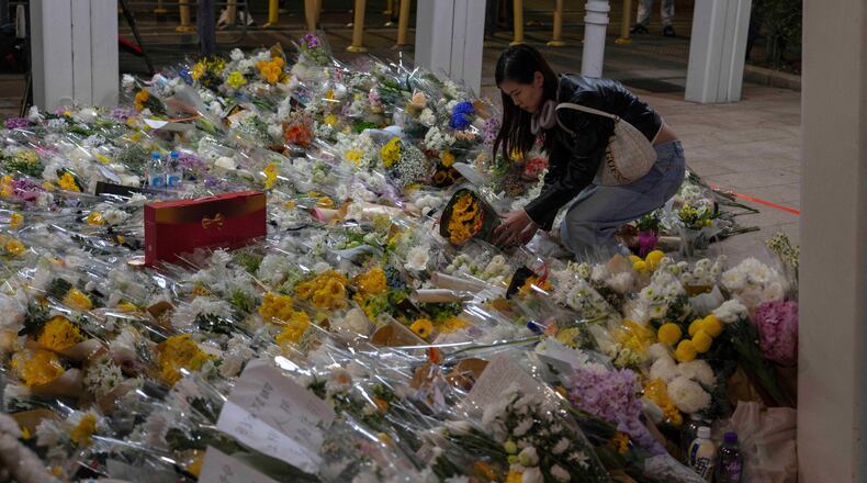 A woman lays flowers near the site of the deadly Wednesday fire at Wang Fuk Court, a residential estate in the Tai Po district of Hong Kong's New Territories on Saturday, Nov. 29, 2025. (AP Photo/Ng Han Guan)