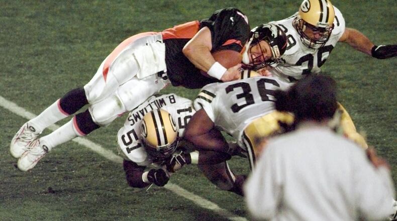 In this Jan. 25, 1998, file photo, Denver Broncos quarterback John Elway is flipped by Green Bay Packers' Brian Williams (51) and Elroy Butler (36) while running for a first down during Super Bowl XXXII at Qualcomm Stadium in San Diego. (AP Photo/Elaine Thompson, File)