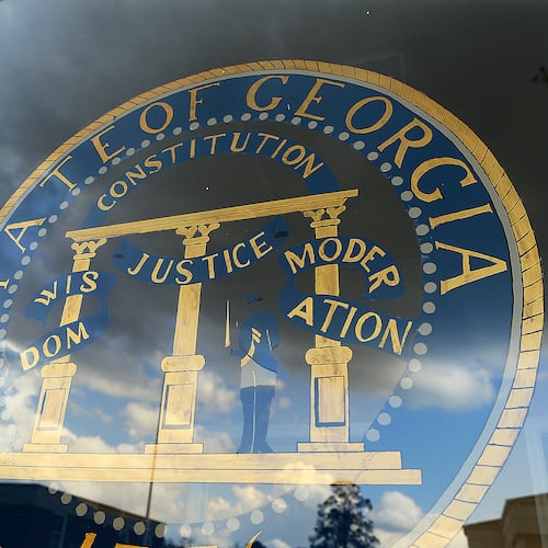 A hand-painted state of Georgia seal with the motto "Wisdom, Justice, Moderation" is on the window of the small Municipal Court building in Pelham. (AJC file)
