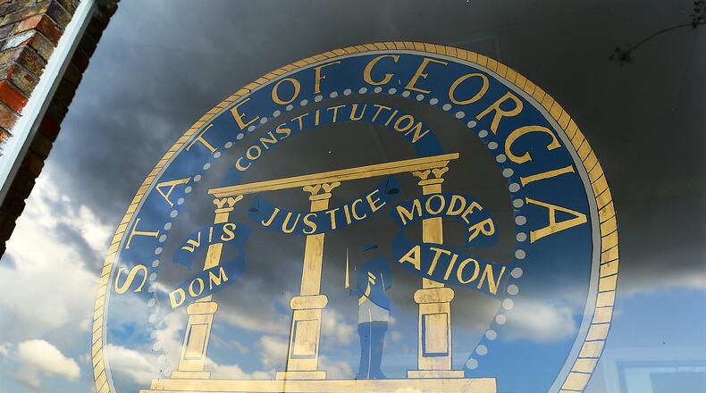 A hand-painted state of Georgia seal with the motto "Wisdom, Justice, Moderation" is on the window of the small Municipal Court building in Pelham. (AJC file)