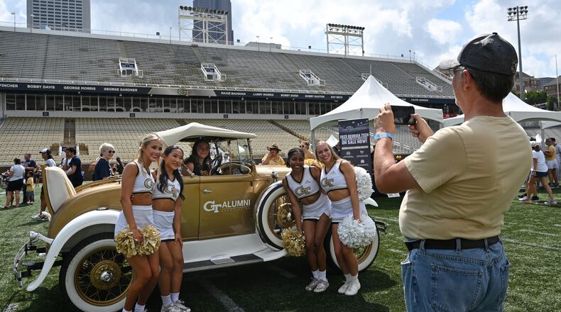 Members of Georgia Tech Cheerleading team pose with a fan in front of Ramblin' Wreck during Georgia Tech football’s annual Fan Day at Bobby Dodd Stadium, Saturday, August 5, 2023, in Atlanta. First Saturday on The Flats presented by Georgia’s Own Credit Union – Georgia Tech football’s annual Fan Day event – featured a plethora of other interactive on-field activities for the whole family, including the opportunity to run out of the Georgia Tech tunnel onto the field like the Yellow Jackets do on gameday, a football toss, ladder drills, combine and tailgate games, an agility course, field goal kicking, a uniform station, 360-degree photo booth and more. (Hyosub Shin / Hyosub.Shin@ajc.com)